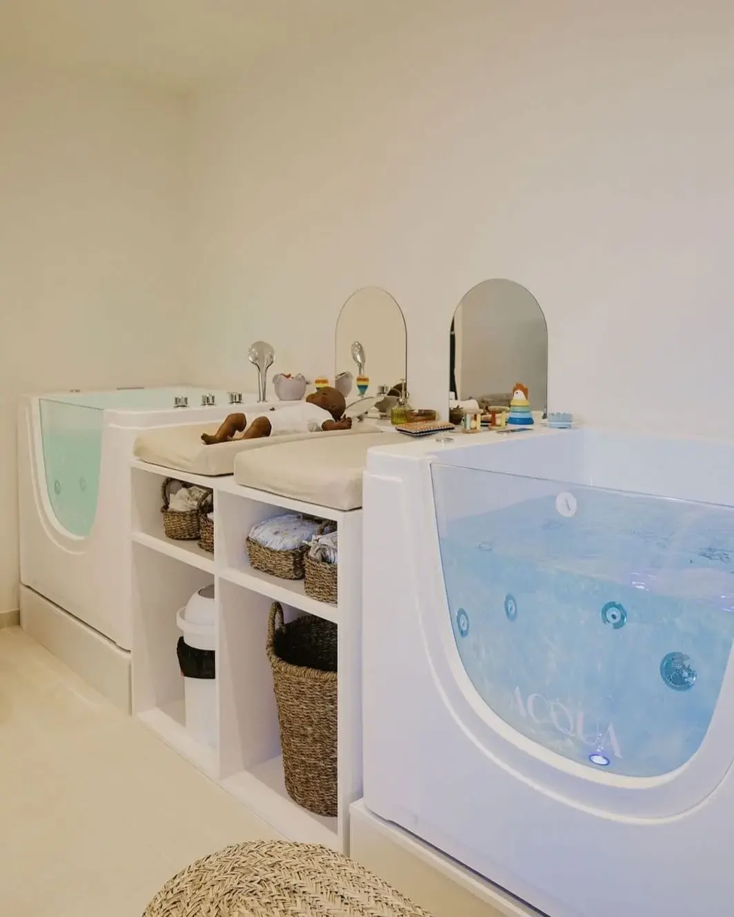 Salle dédiée aux soins pour bébés avec bains spécialisés, tables à langer et rangement en paniers