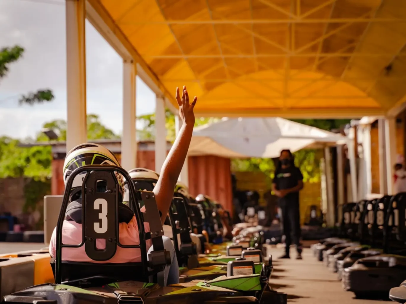 Personne assise dans un kart levant le bras sur la ligne de départ, prête à commencer la course