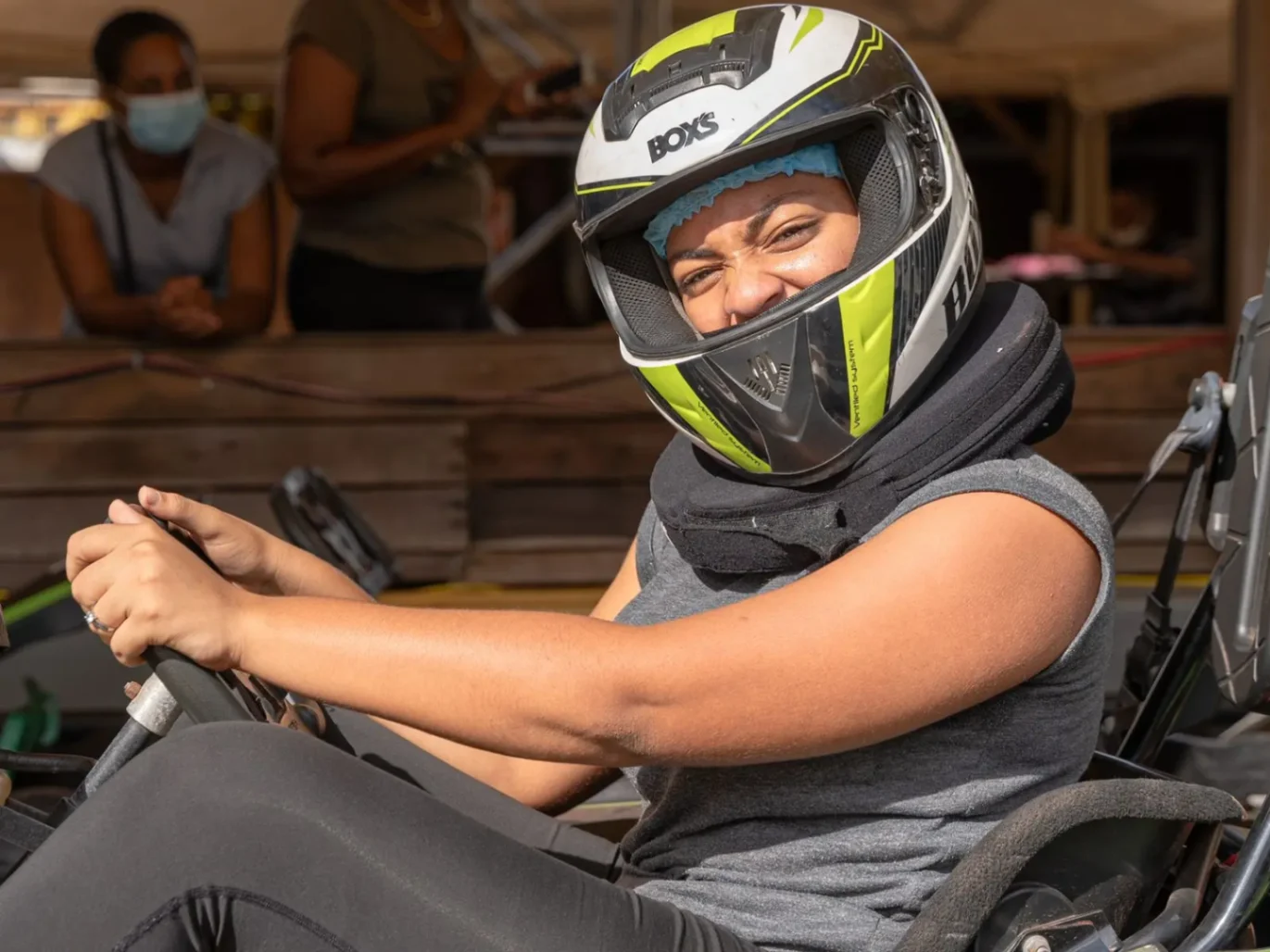 Personne assise dans un kart, portant un casque de sécurité et souriant avant le départ