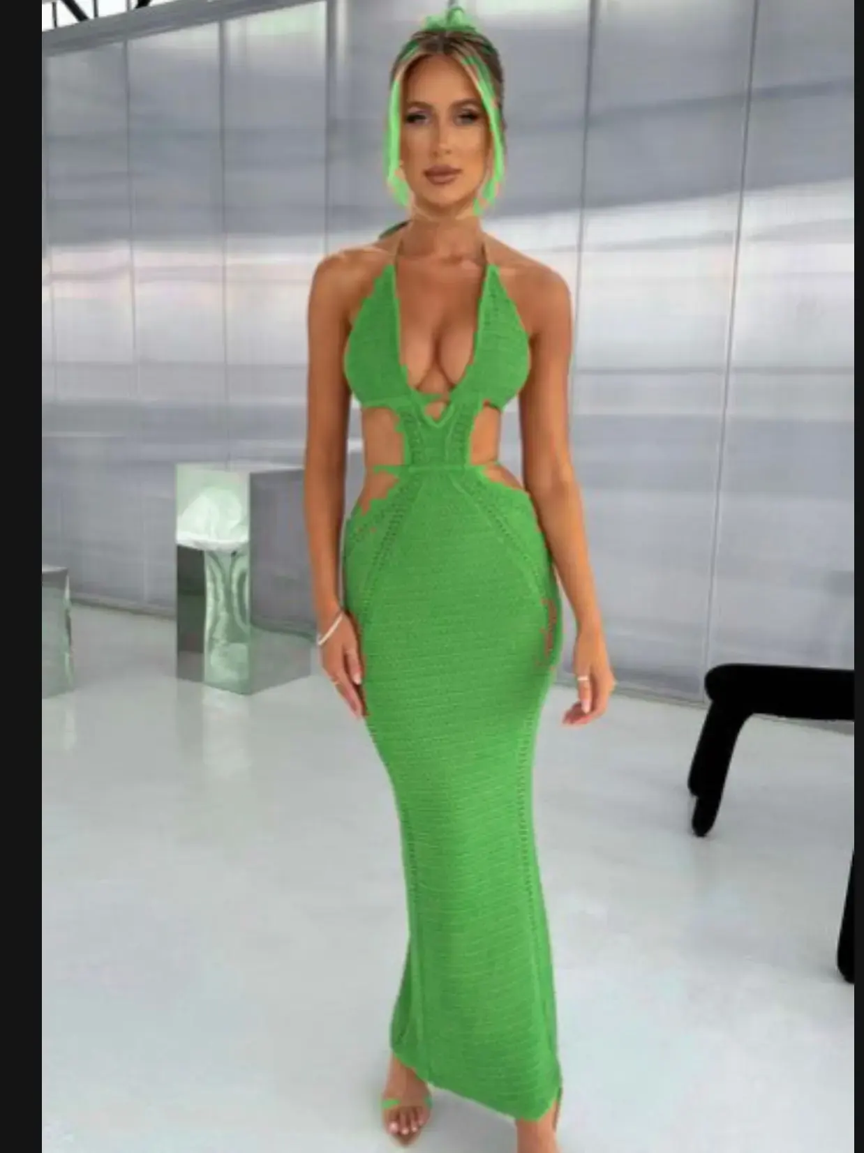 Femme portant une robe longue verte avec découpes sur les côtés et décolleté plongeant, style soirée moderne