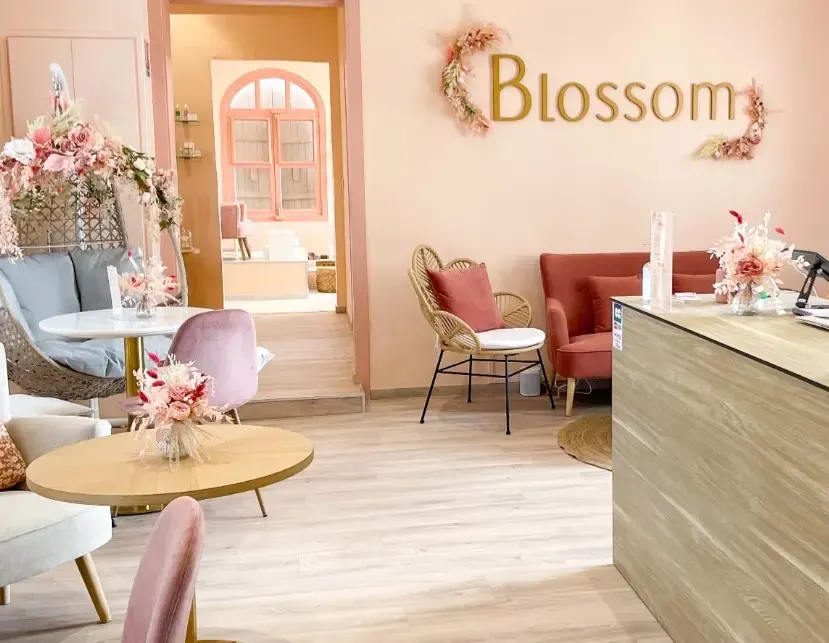 Intérieur d’un salon de beauté Blossom dans des tons rose et bois, avec espace détente et décoration florale