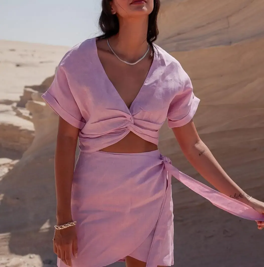 Ensemble féminin lilas composé d’un top noué et d’une jupe portefeuille dans un décor désertique.