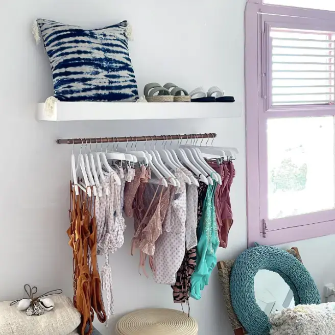 Portant de maillots de bain colorés dans une boutique au style épuré avec étagère murale et coussin tie-dye.