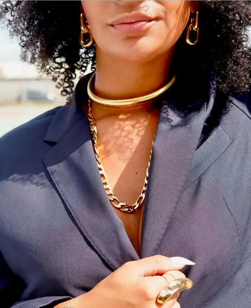 Femme portant un collier doré, une chaîne dorée et des boucles d’oreilles assorties pour un look chic et élégant.