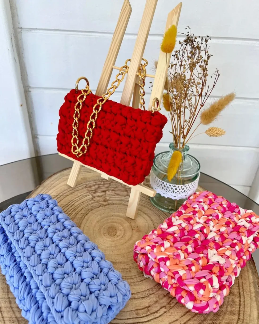 Petit sac en crochet rouge avec chaîne dorée, présenté sur un support en bois – sac artisanal fait main