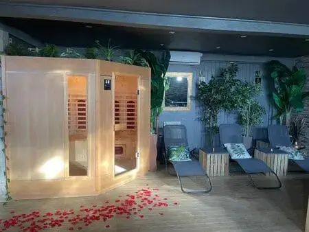 Espace détente avec sauna en bois, transats et pétales de fleurs chez Elite Spa