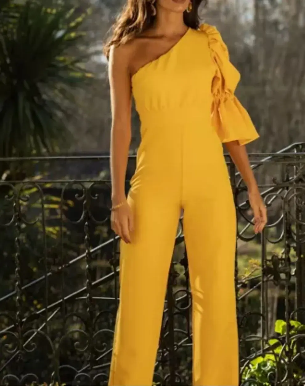 Femme portant une combinaison jaune asymétrique, tenue élégante pour événement ou soirée estivale.