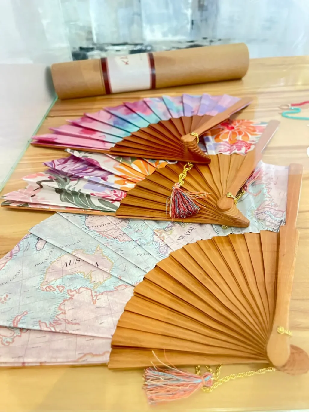 Éventails artisanaux colorés en bois et tissu imprimé exposés sur une table, accessoires d’été élégants.