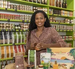 Portrait d’une femme dans une boutique Kreyol Market entourée de produits créoles artisanaux et gastronomiques.