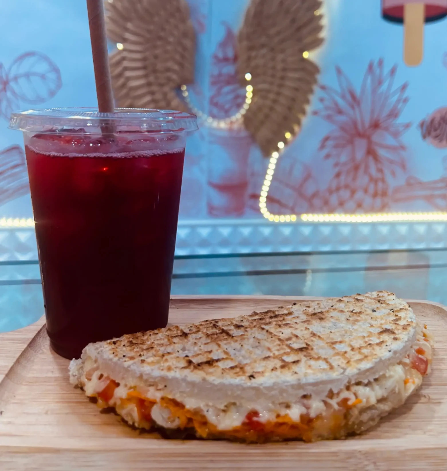 Boisson bissap fraîche accompagnée d’un panini créole gratiné, servi sur plateau chez La Casa de Paletas.