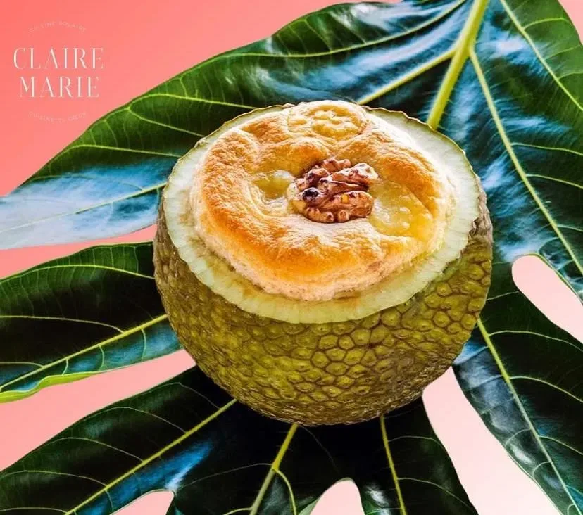 Dessert soufflé présenté dans un fruit à pain ouvert, posé sur une grande feuille verte, création culinaire de Claire Marie.