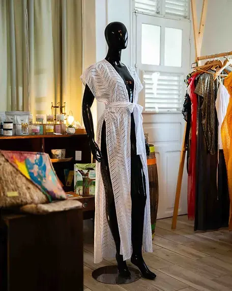 Mannequin portant une longue robe blanche en crochet dans une boutique de créateurs locaux.