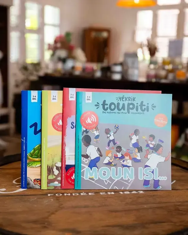 Collection de livres pour enfants Toupiti exposée sur un tonneau dans une boutique chaleureuse.
