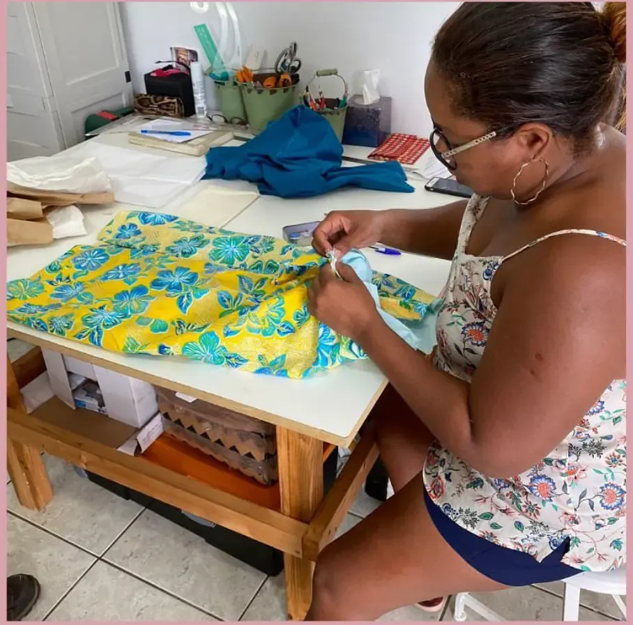 Femme en train de travailler un tissu fleuri jaune et bleu sur une table de couture dans un atelier