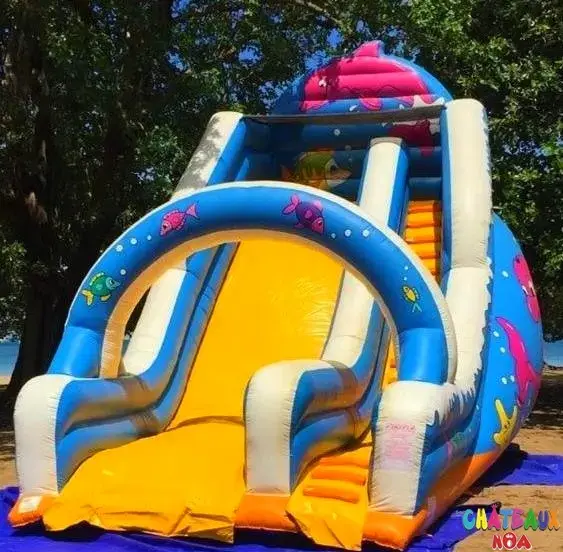 Grand toboggan gonflable sur le thème de l’océan, décoré de poissons colorés et d’une glissade jaune.