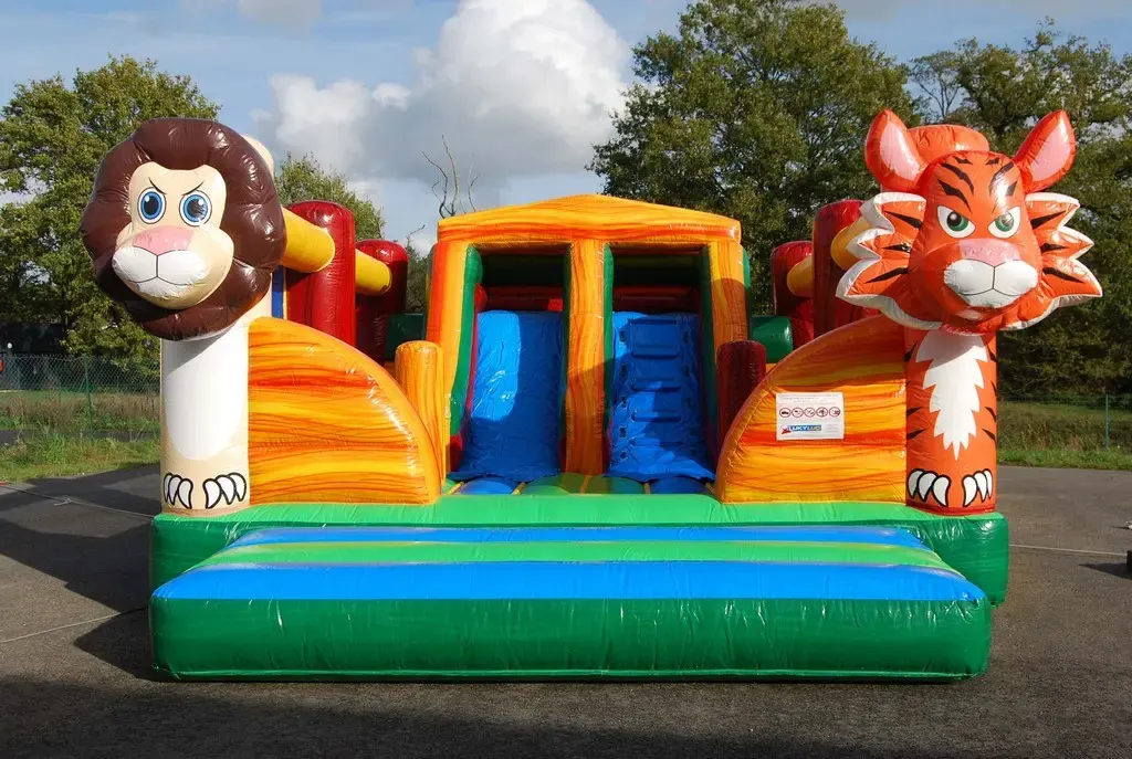 Château gonflable aux couleurs de la jungle avec une tête de lion et une tête de tigre à l’entrée.