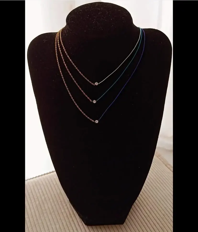 Colliers minimalistes en fil coloré avec perle fine exposés sur un présentoir noir