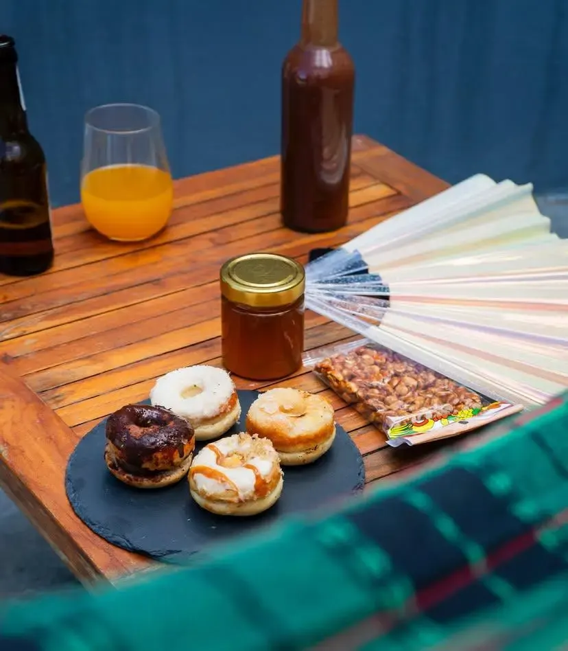 Pot de miel artisanal Maison Eritaj posé sur une table en bois avec donuts et boissons