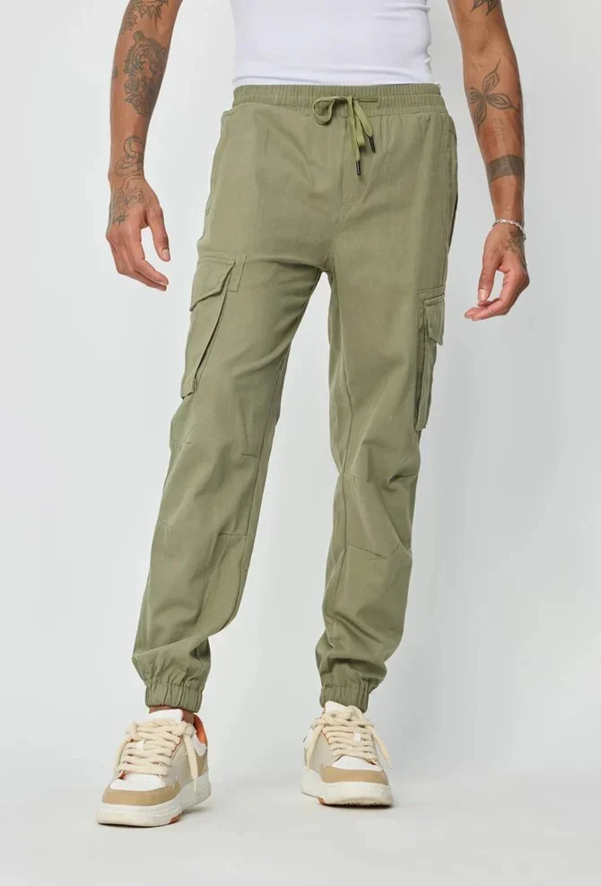 Homme portant un pantalon cargo vert à poches, style streetwear moderne