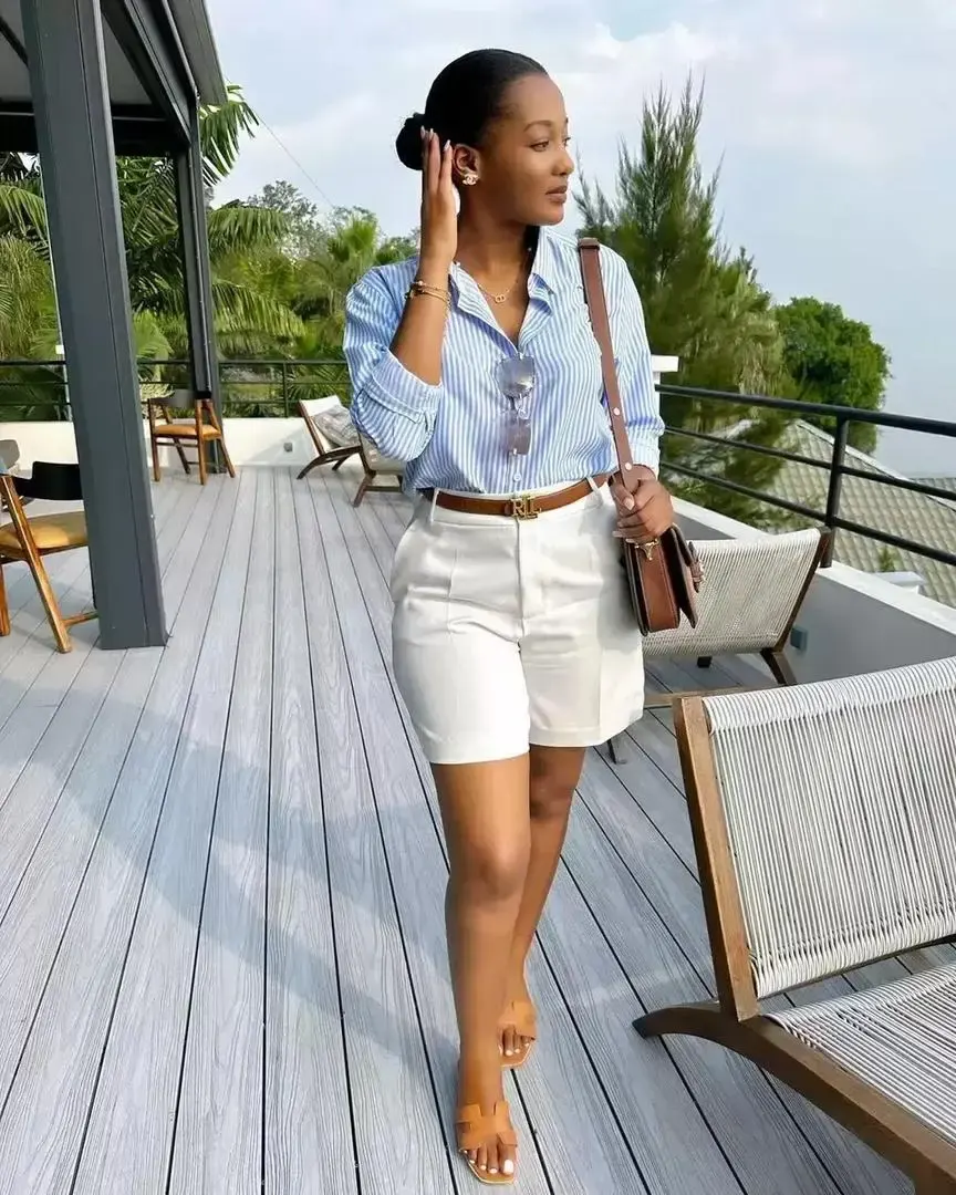 Femme portant une tenue chic composée d’un short blanc et d’une chemise rayée bleue