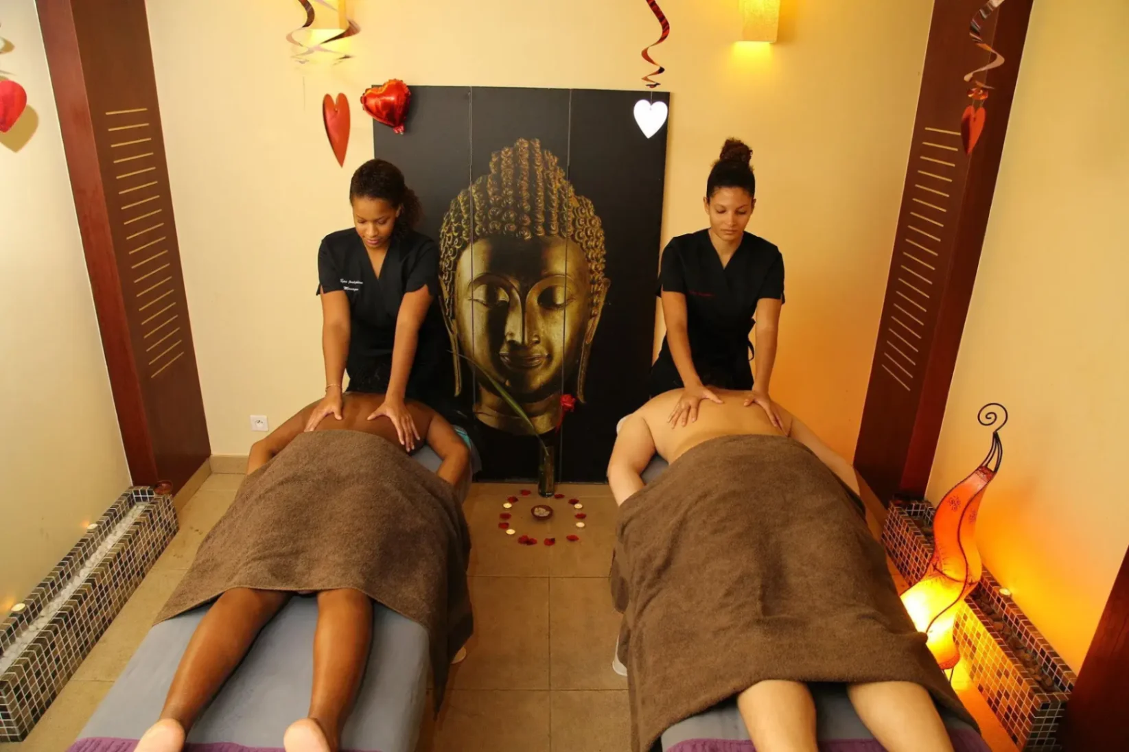 Deux praticiennes réalisant un massage duo relaxant dans une salle de spa décorée, ambiance zen