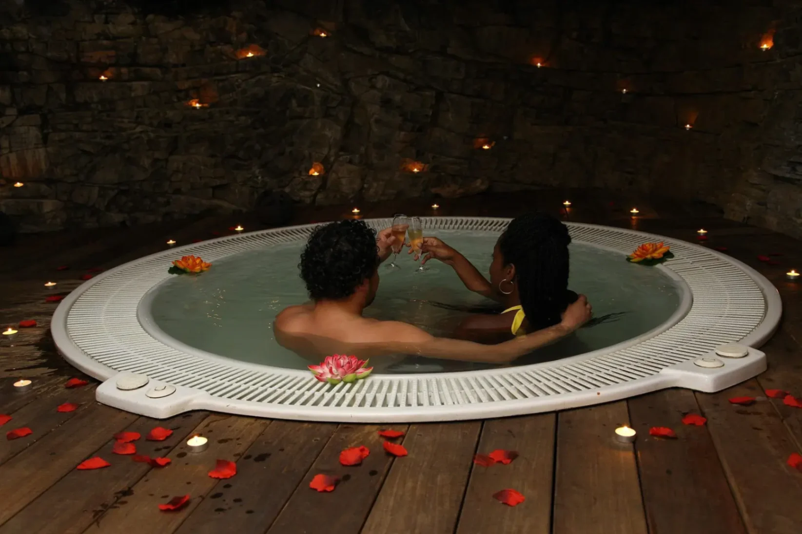 Couple profitant d’un jacuzzi romantique décoré de pétales et de bougies.
