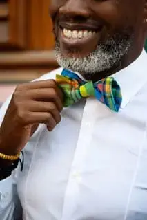 Homme souriant portant un nœud papillon en madras, accessoire traditionnel créole
