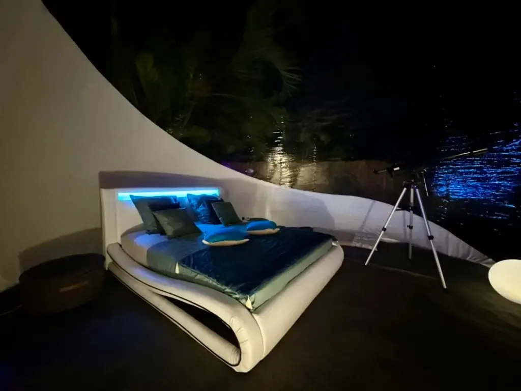 Intérieur d’une bulle de nuit avec lit lumineux et télescope en Martinique