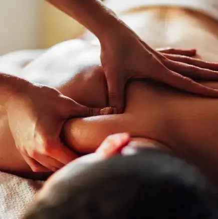 Mains d’une praticienne effectuant un massage relaxant du dos en gros plan.