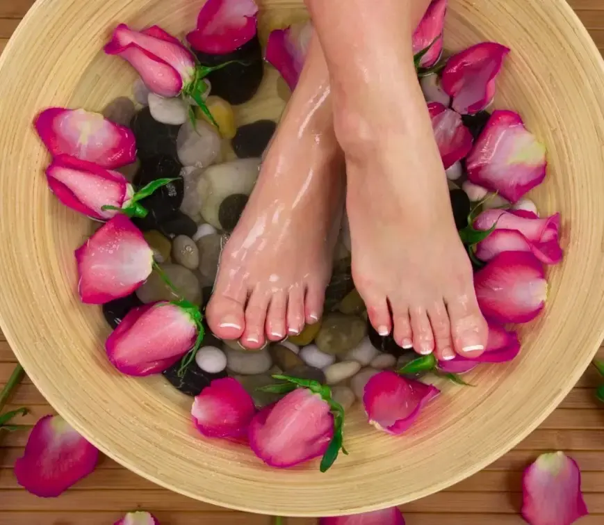 Pieds reposant dans un bain d’eau tiède avec pétales de rose pour un soin bien-être