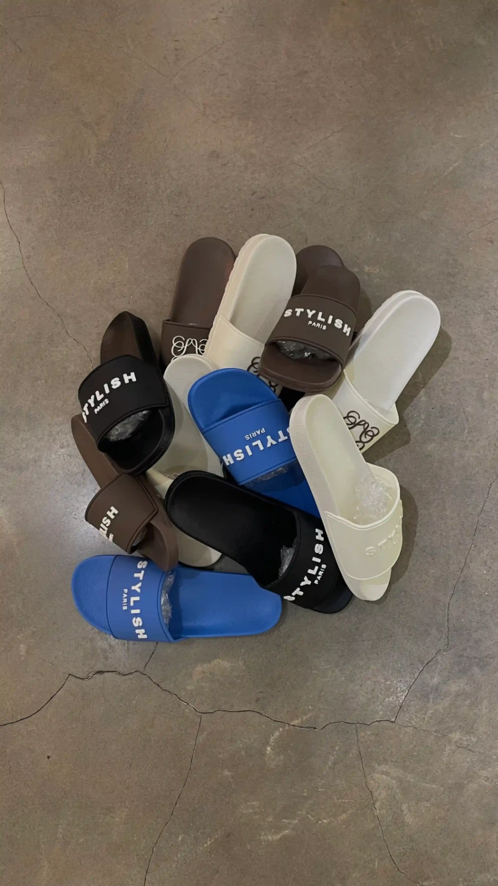 Ensemble de claquettes Stylish Paris de différentes couleurs disposées en cercle sur un sol en béton.