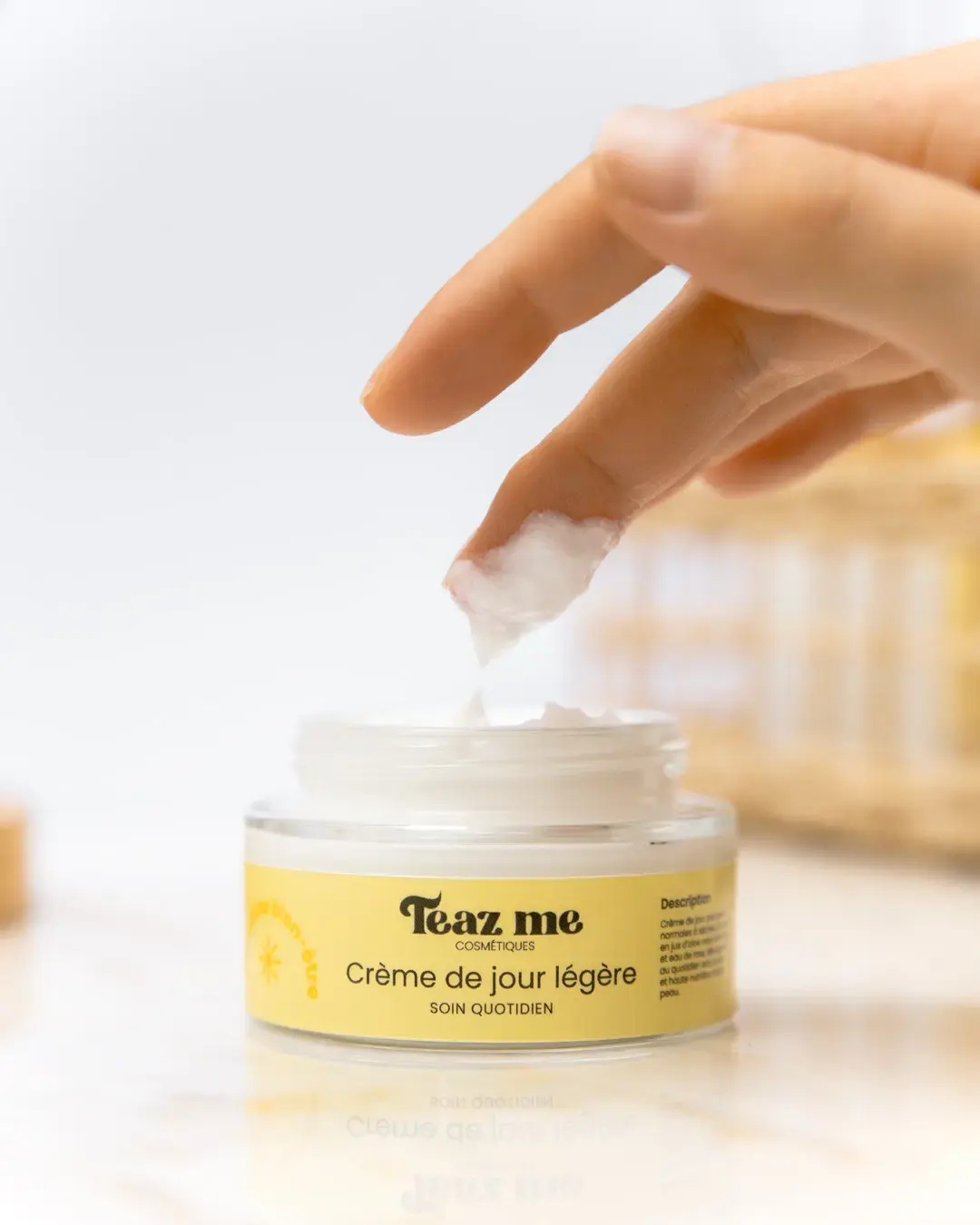 Doigt prélevant la crème de jour légère Teaz Me dans un pot ouvert, montrant la texture du soin.