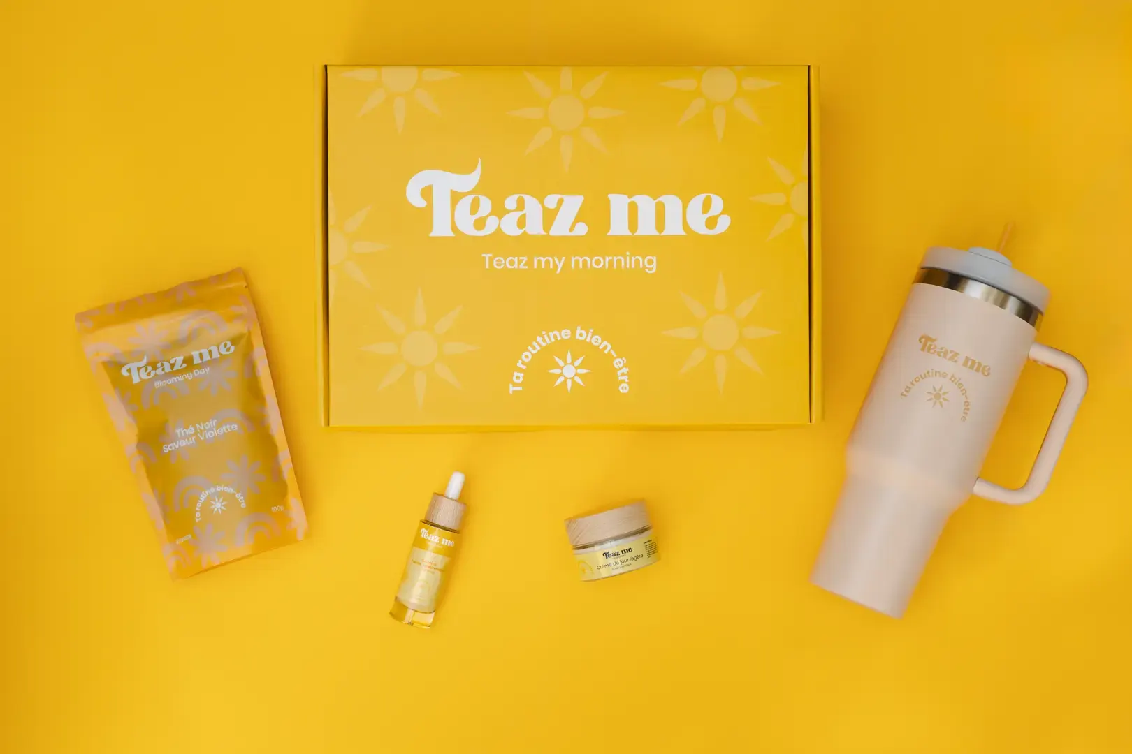 Coffret jaune Teaz Me « Teaz my morning » entouré de produits bien-être : tisane, sérum, crème de jour et mug isotherme.
