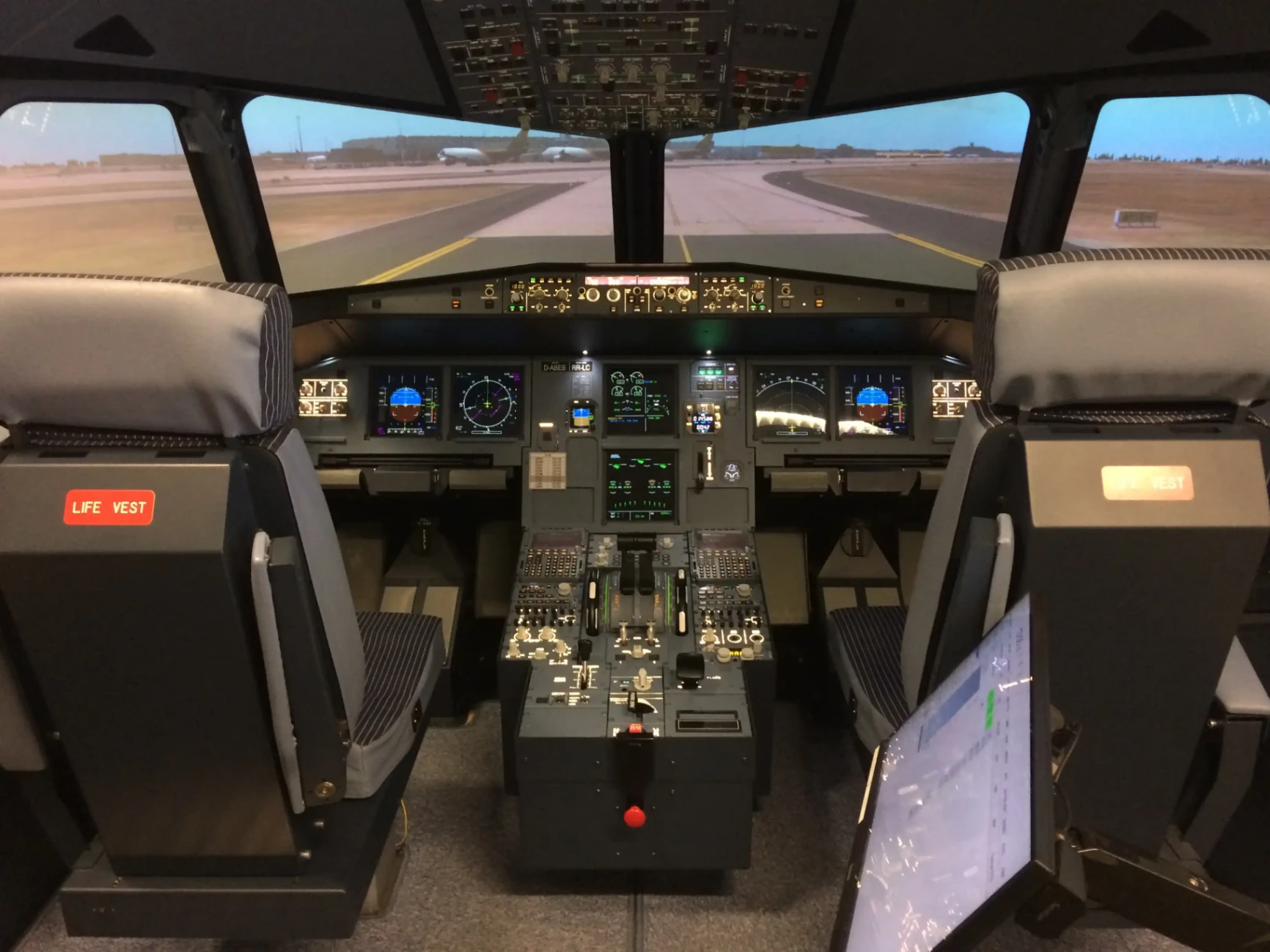 Cockpit complet d’un simulateur de vol Airbus A320 avec écrans de navigation allumés et vue de piste devant le pare-brise.