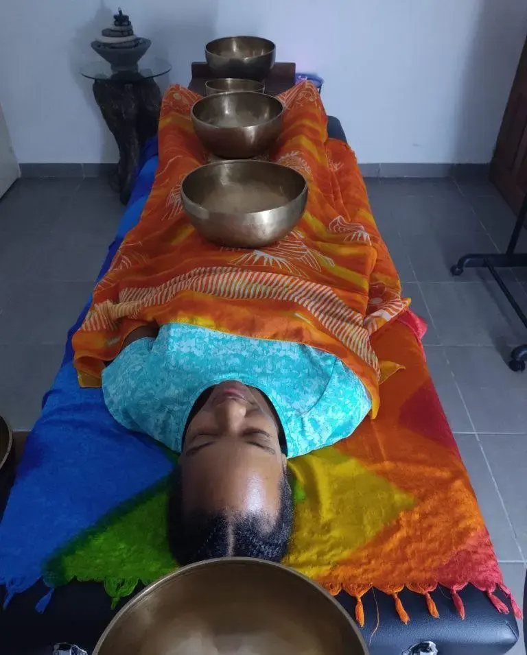 Personne allongée sur une table de soin avec plusieurs bols tibétains posés sur le corps lors d’une séance de sonothérapie.