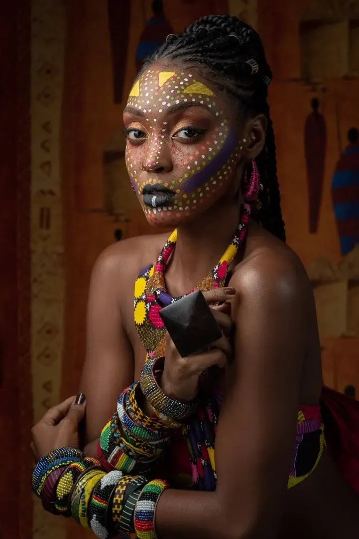 Femme portant un maquillage ethnique inspiré d’art tribal et des accessoires colorés en perles.