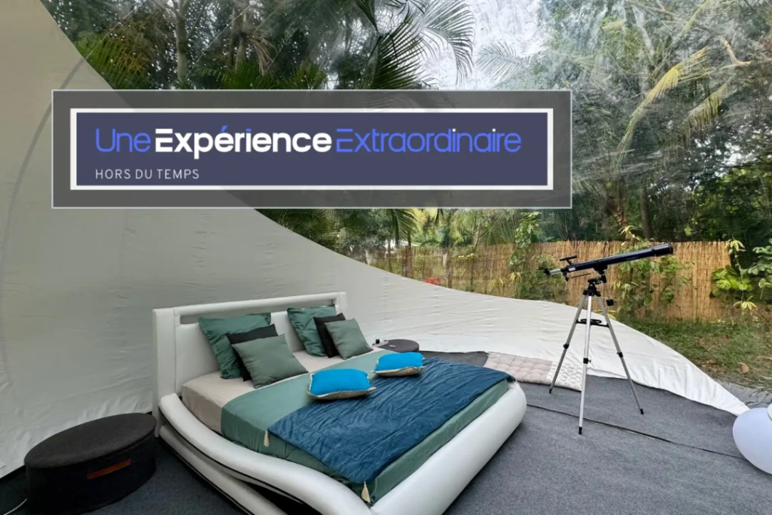 Intérieur d’une bulle transparente avec lit design et télescope, offrant une expérience immersive en pleine nature.