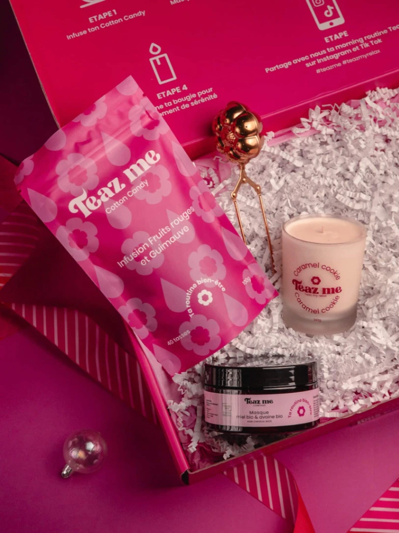 Coffret bien-être Teaz Me Cotton Candy avec infusion fruits rouges, bougie parfumée caramel cookie et masque capillaire au miel, présenté dans un décor rose gourmand.
