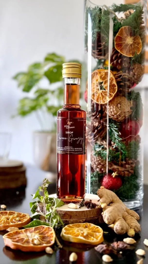 Bouteille de sirop artisanal au gingembre et épices, présentée avec agrumes séchés et éléments décoratifs naturels.
