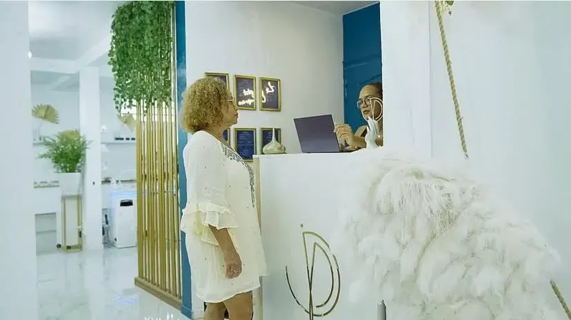 Accueil chaleureux dans un institut de beauté et de bien-être, cliente échangeant avec une professionnelle à la réception.