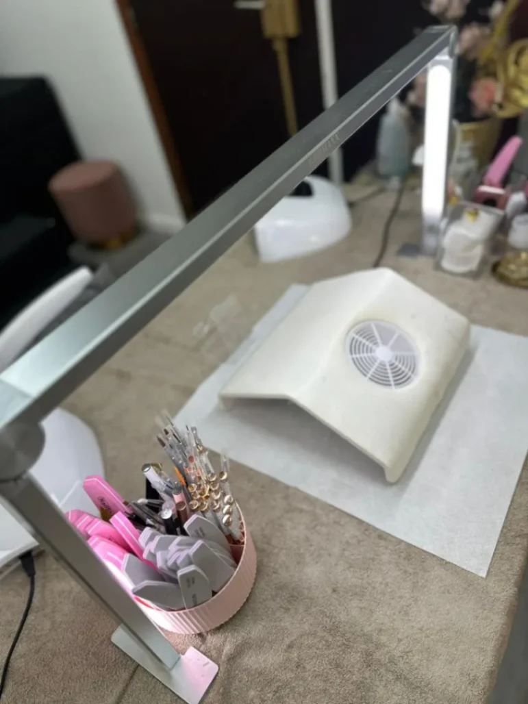 Poste de manucure professionnel avec lampe UV, aspirateur à poussière et outils de soin des ongles.