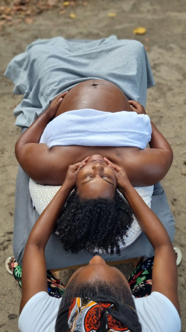 Femme enceinte allongée recevant un massage prénatal relaxant, dans un environnement calme et naturel.