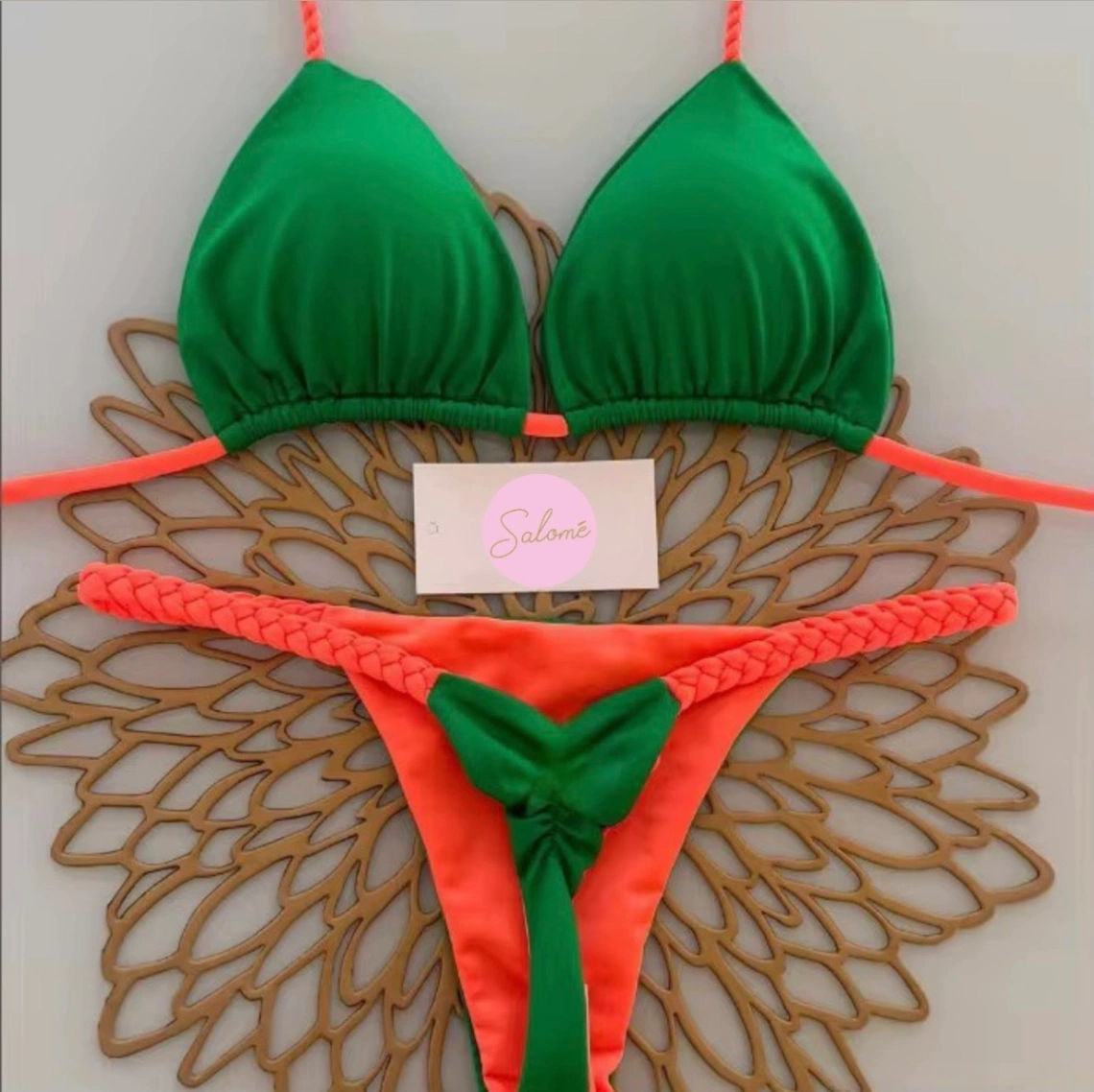 Bikini deux pièces vert et corail avec liens tressés, présenté à plat sur fond décoratif