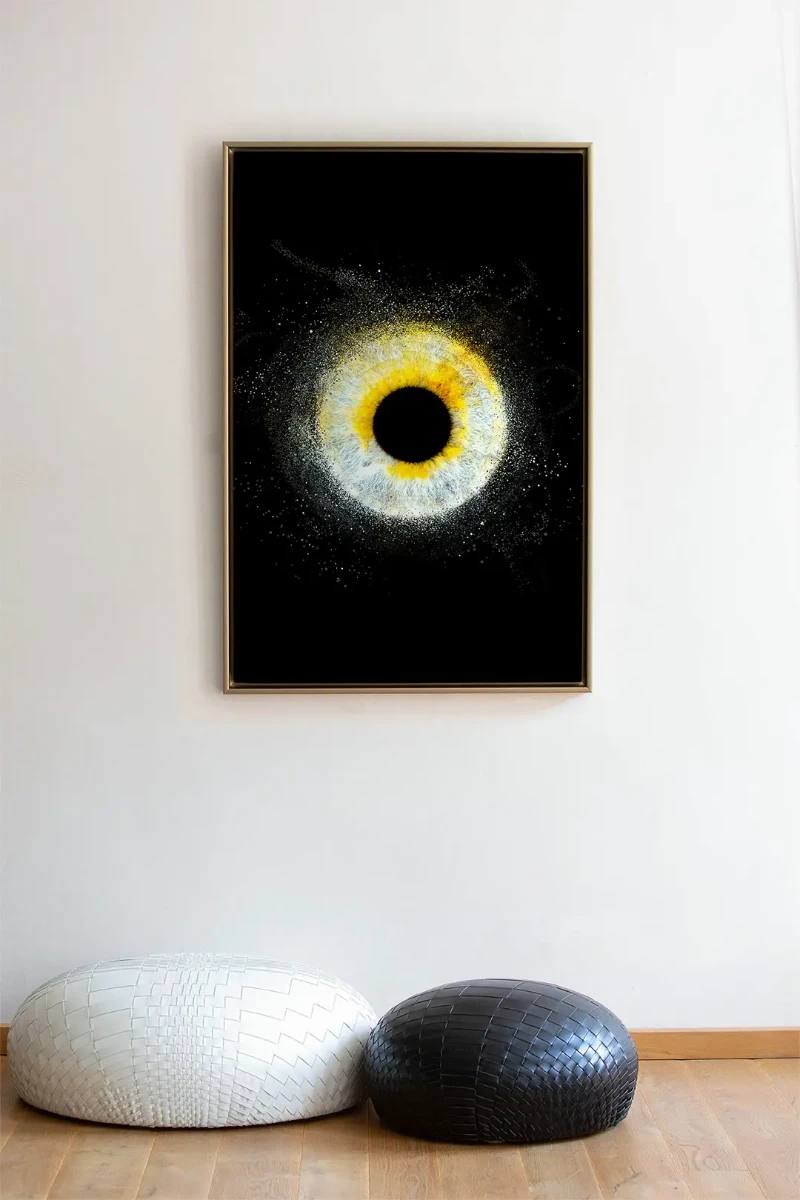 Tableau décoratif représentant un iris blanc et jaune sur fond noir, accroché sur un mur clair au-dessus de poufs design.