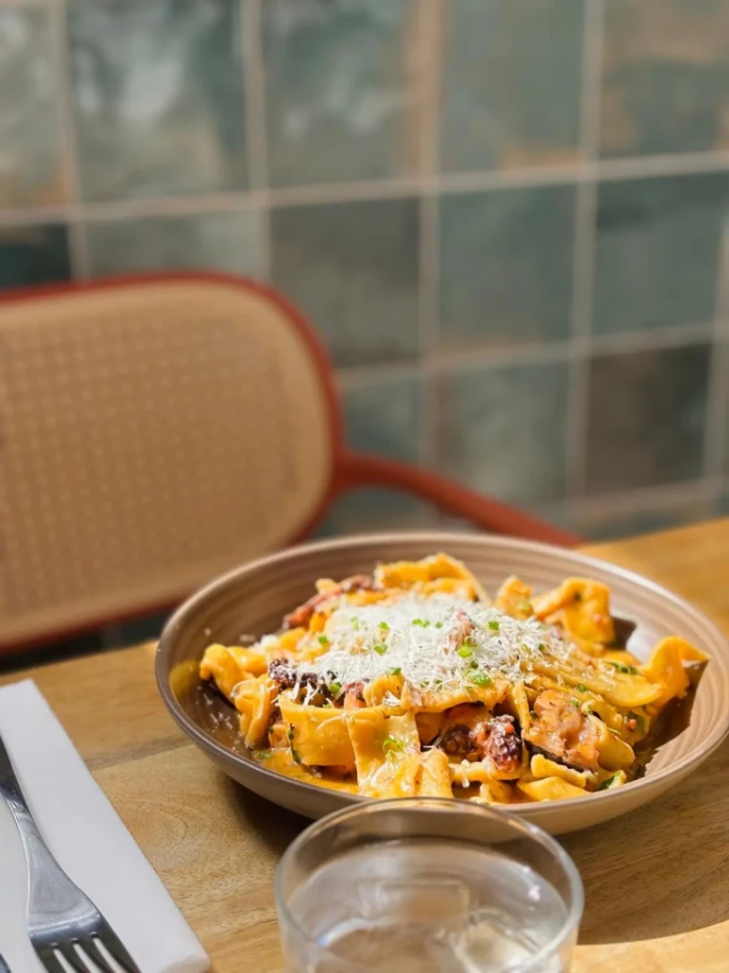 Plat de pappardelle au poulpe nappées d’une sauce tomate et généreusement recouvertes de parmesan.
