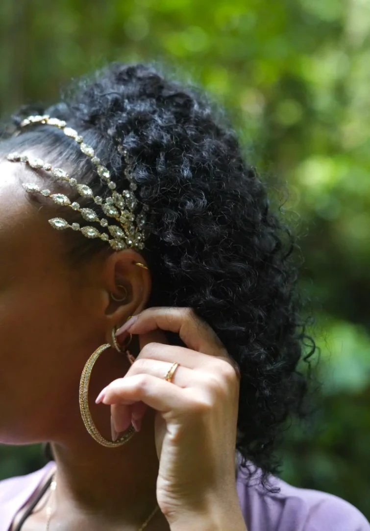 Zoom sur des boucles d’oreilles créoles et accessoires cheveux portés par une femme.