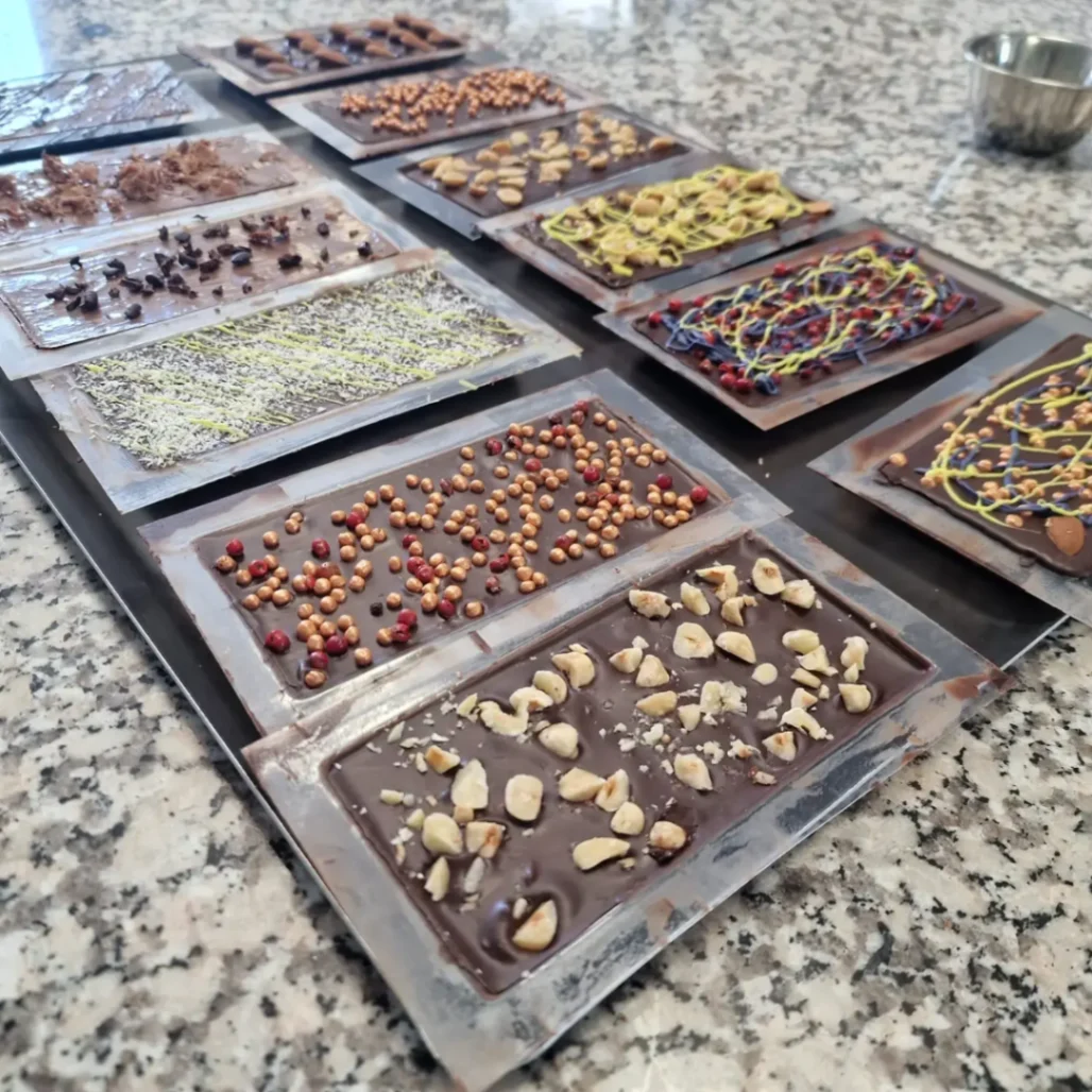 Assortiment de tablettes de chocolat artisanal garnies de fruits secs et toppings créatifs.