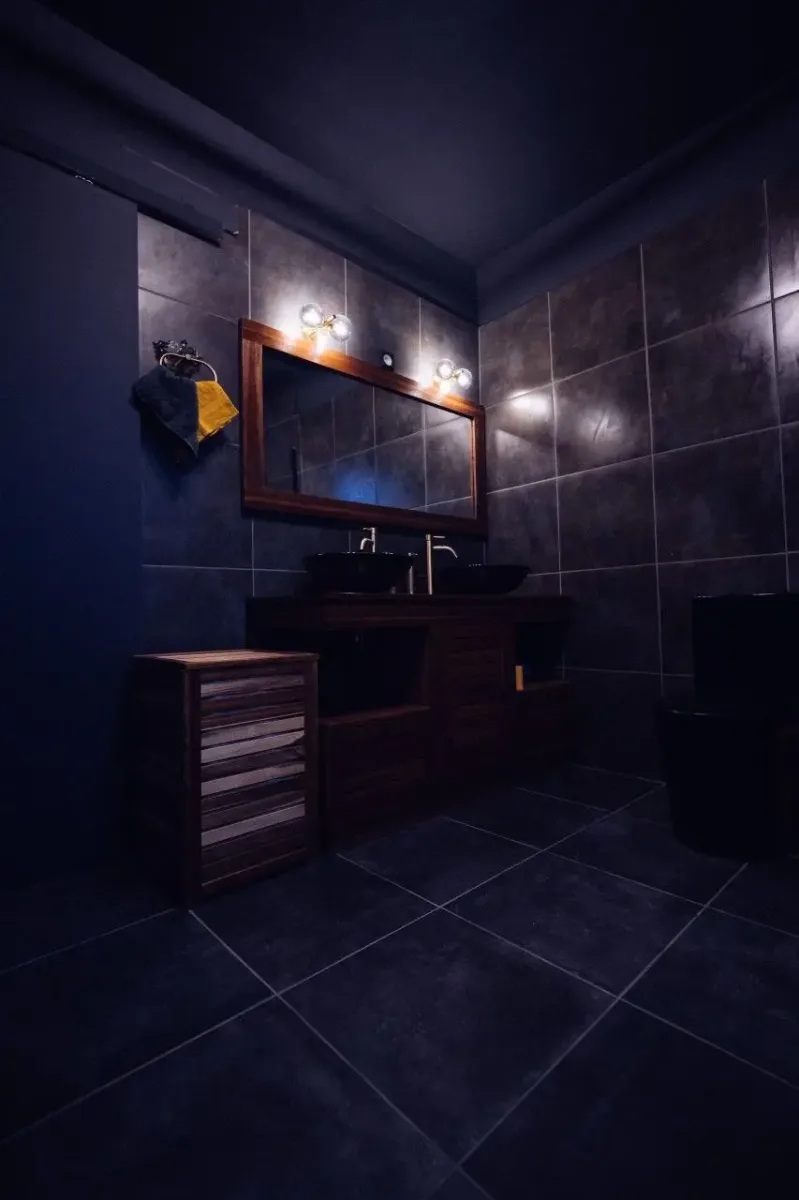 Salle de bain moderne avec double vasque en bois et ambiance tamisée dans une suite romantique en Martinique