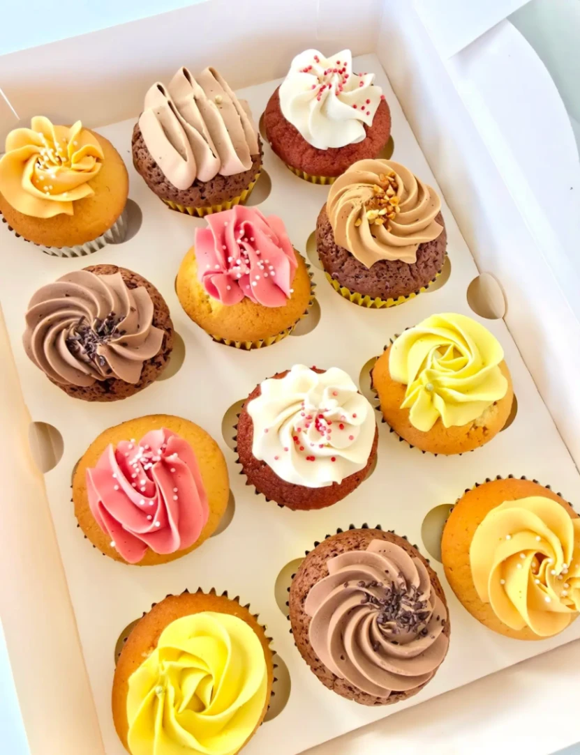 Assortiment de 12 cupcakes artisanaux aux saveurs variées avec décorations florales et gourmandes en Martinique.