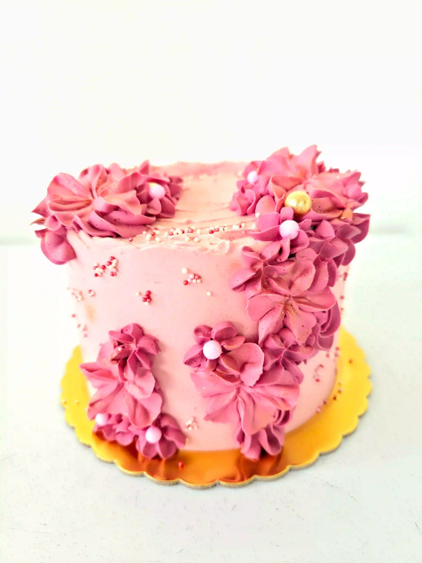 Gâteau artisanal décoré de fleurs en crème rose, idéal pour un anniversaire, un baptême ou une célébration en Martinique.